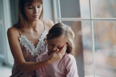 Close-up of mother and daughter against window