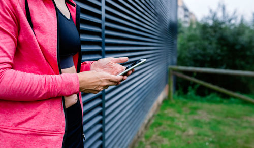 Midsection of man using mobile phone while standing on plant