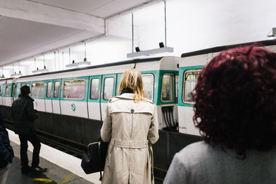 Rear view of woman standing by train against sky