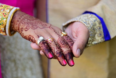 Midsection of bride and bridegroom holding hands