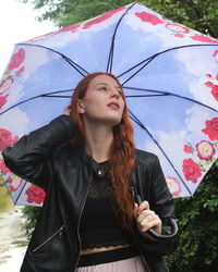 Portrait of a beautiful young woman with a colorful umbrella in rain
