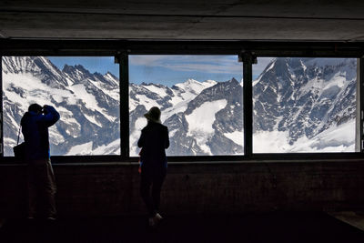 Rear view of people looking at snowcapped mountains at observation point