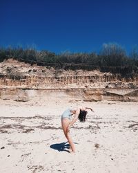 Young woman on beach against clear sky during sunny day