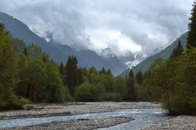 Scenic view of river amidst mountains against cloudy sky