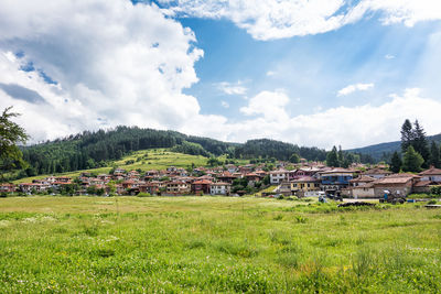 Houses on field by buildings against sky