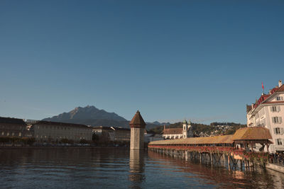 Buildings at waterfront against clear blue sky