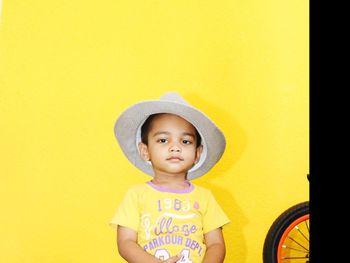 Portrait of innocent boy wearing hat against yellow background