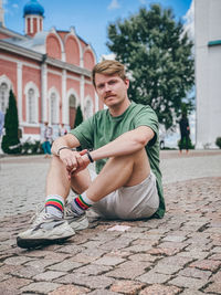 Young man sitting on building in city