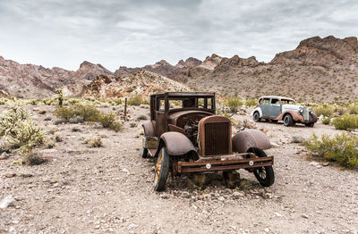 Abandoned truck on field against mountains