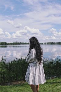 Rear view of woman standing in lake against sky