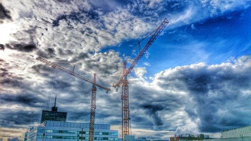 Low angle view of crane against cloudy sky