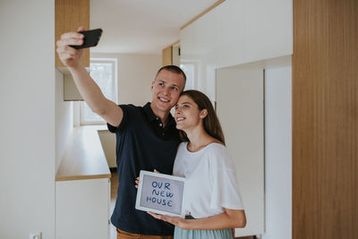Smiling young couple with digital tablet photographing at home