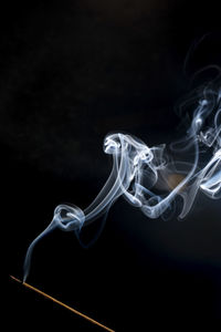 Close-up of emitting smoke against black background