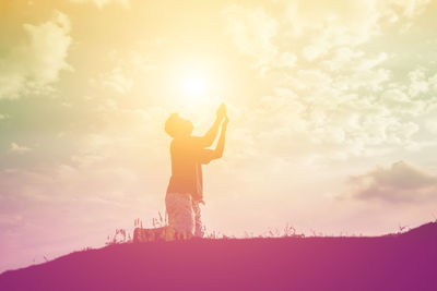 Silhouette woman standing on field against sky during sunset