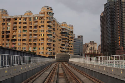 Railroad tracks amidst buildings in city against sky