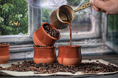 Cropped hand pouring coffee in container