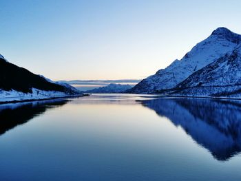 Scenic view of lake and snowcapped mountains against clear blue sky