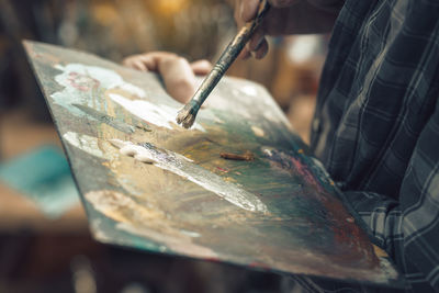 Midsection of man holding paintbrush with painting