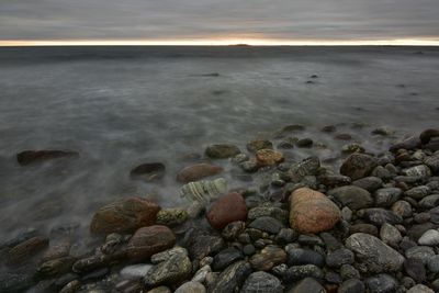 Surface level of rocks at beach against sky during sunset
