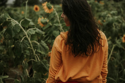 Rear view of young woman standing at sunflower farm