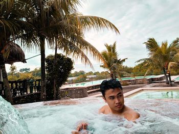 Shirtless man swimming in pool against sky