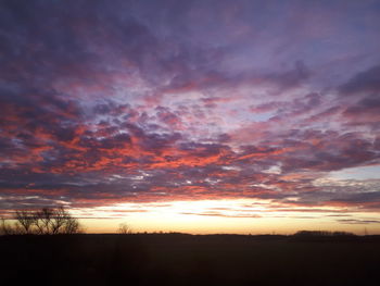 Silhouette landscape against dramatic sky during sunset