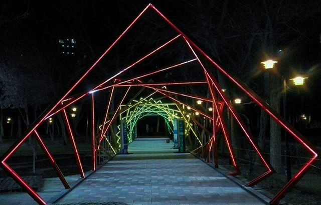 illuminated, night, the way forward, connection, built structure, diminishing perspective, arch, lighting equipment, architecture, bridge - man made structure, street light, multi colored, vanishing point, transportation, tree, long exposure, bridge, outdoors, no people, light trail