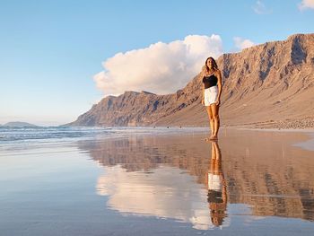 Woman standing on shore against sky