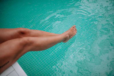 Low section of woman relaxing in swimming pool