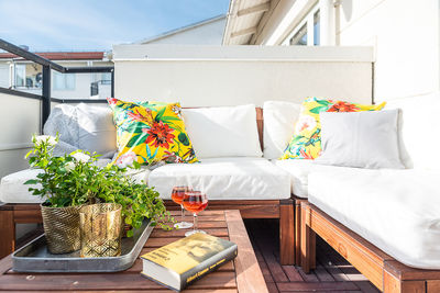 Book and drink by potted plants on side table by sofa in patio