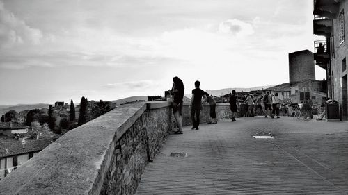 People walking on road in city against sky