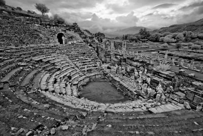 Scenic view of tourists exploring pamukkale ruins against cloudy sky