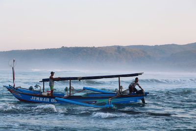 Fishing boat in sea against clear sky