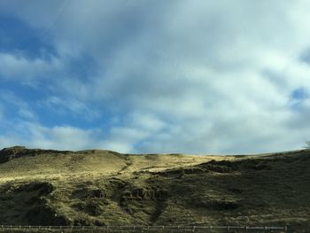 Low angle view of landscape against cloudy sky