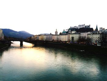 River by buildings against clear sky