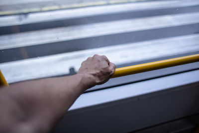 Cropped hand of man holding railing by window