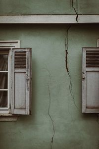 Crack in green wall between two old windows 
