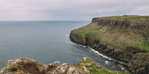 Scenic view of sea by cliff against sky
