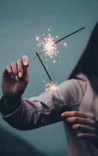 Midsection of woman holding sparkler at night