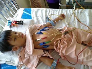 High angle view of boy lying on bed at hospital