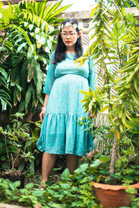 Portrait of a smiling young woman standing against plants