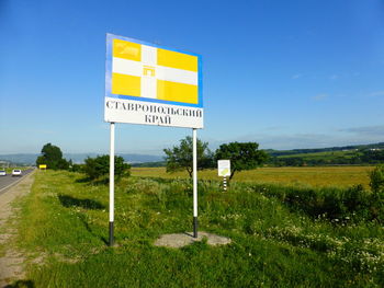 Road sign on field against sky