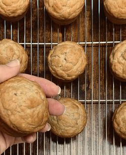 Baked muffins on a rack and hand holding one muffin