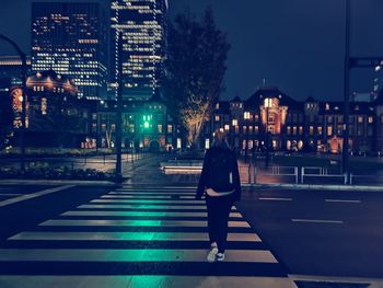 Rear view of man walking on road at night