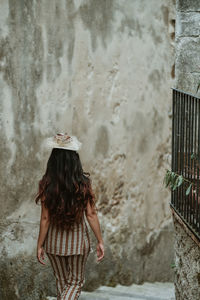 Rear view of woman standing against wall