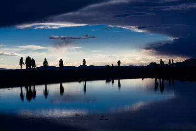 Silhouette people on water against sky