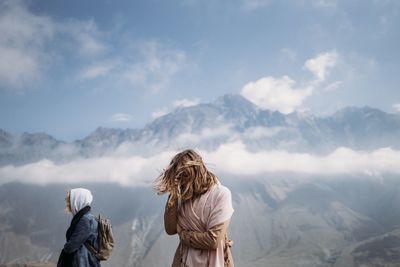 Rear view of woman standing on mountain against sky