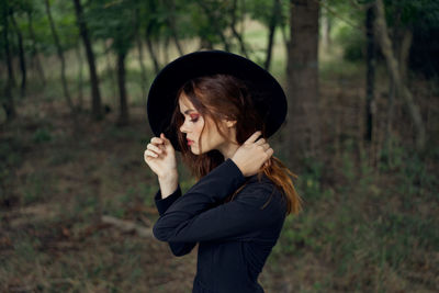 Young woman standing against trees