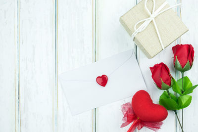 High angle view of envelope with red roses on table