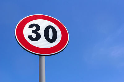 Low angle view of speed limit sign against clear blue sky